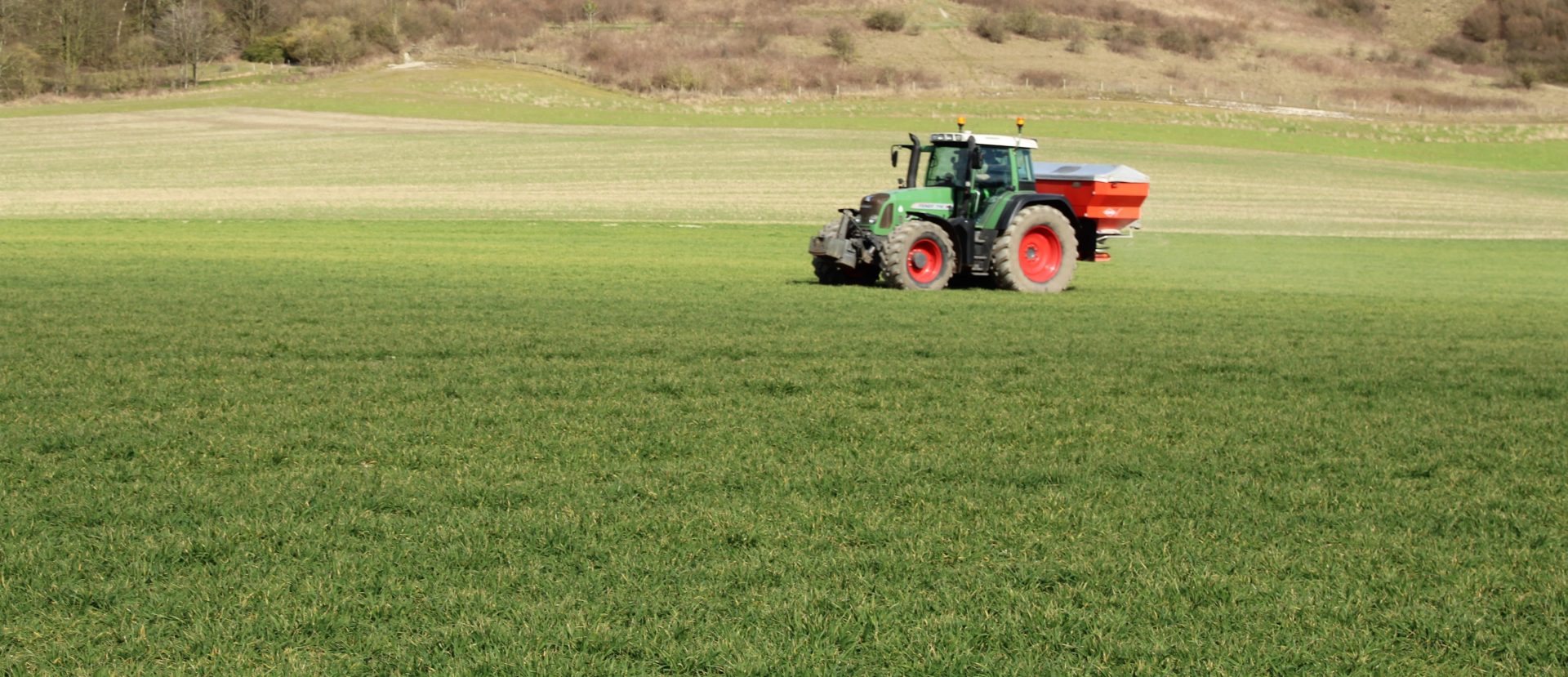 Tractor driving across field spraying fertiliser